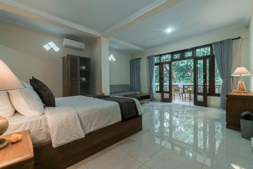 a bedroom with a large bed and a living room at Vaneka Garden House in Ubud