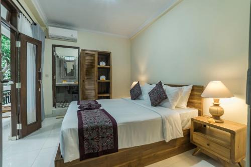 a bedroom with a bed and a lamp and a window at Vaneka Garden House in Ubud