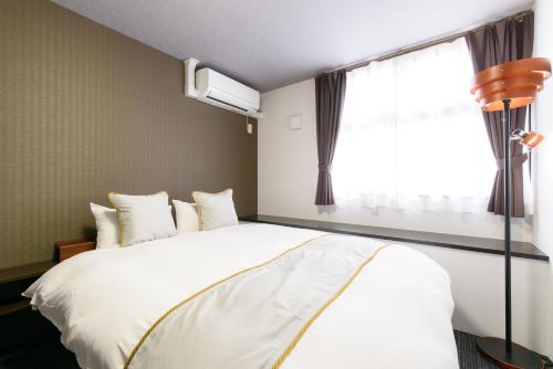 a bedroom with a large white bed and a window at JP INN Kyotoeki Kita Gakurincho in Kyoto