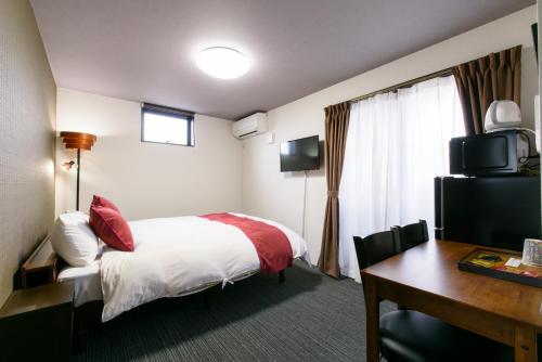 a hotel room with a bed and a desk and a table at JP INN Kyotoeki Kita Gakurincho in Kyoto