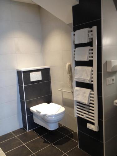 a small bathroom with a toilet and towels at Cit'Hotel Du Port Rhu in Douarnenez