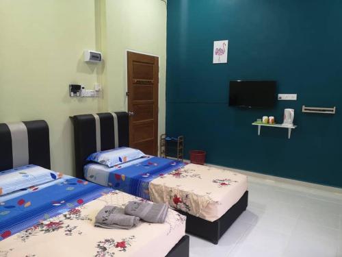 a room with two beds and a flat screen tv at VILLA SENTOSA in Kuala Terengganu