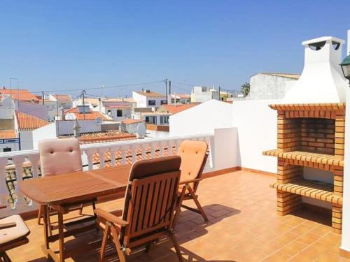 a balcony with a wooden table and chairs and a fire place at Retreat with Terrace and View in Espiche #1887 in Espiche