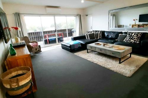 a living room with a black couch and a table at Modern 3 bedroom apartment, beach, surf & shops in Cape Woolamai