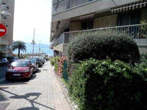 une voiture rouge garée à côté d'un trottoir à côté d'un bâtiment dans l'établissement Appartement Promenade des Bains, à Saint-Raphaël