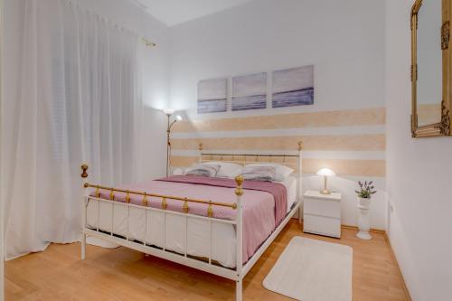 a white bedroom with a bed and a window at Apartments Riva Lucija in Split