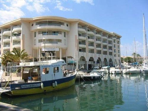 a boat is docked in front of a large building at Résidence du Port - Borghese in Fréjus