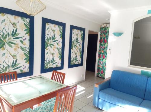 a dining room with a glass table and a blue couch at Résidence du Port - Borghese in Fréjus