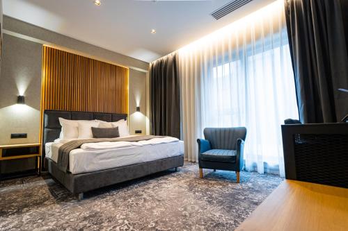une chambre d'hôtel avec un lit et une chaise dans l'établissement Hugo Hotel, à Satu Mare