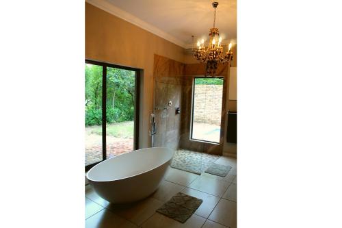 a bathroom with a large tub and a chandelier at Casa Cara Resort in Parys