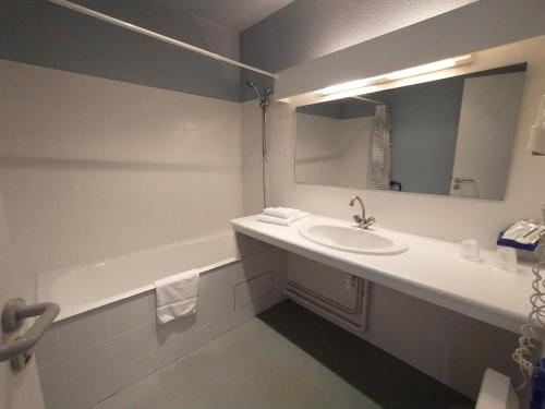 La salle de bains est pourvue d'un lavabo, d'une baignoire et d'un miroir. dans l'établissement Les Terrasses du petit Nérac, à Nérac