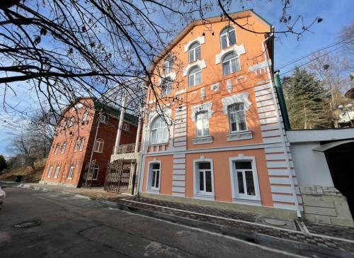 ein orangefarbenes Gebäude mit weißen Fenstern auf einer Straße in der Unterkunft Guest House Kaskad in Kislowodsk