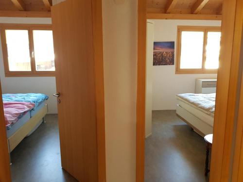 Habitación con 2 camas y 2 ventanas. en Neuwertige 3 ½ Zimmer-Wohnung in Zillis/Andeer, en Zillis