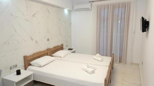 a bedroom with two beds and a white wall at Constantine Fortezza Rooms in Rethymno