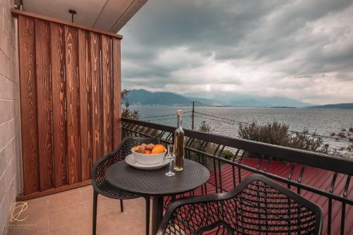 a table with a bottle of wine and a bowl of oranges on a balcony at Barka B'n'B - Elegant Seaview Rooms in Herceg-Novi
