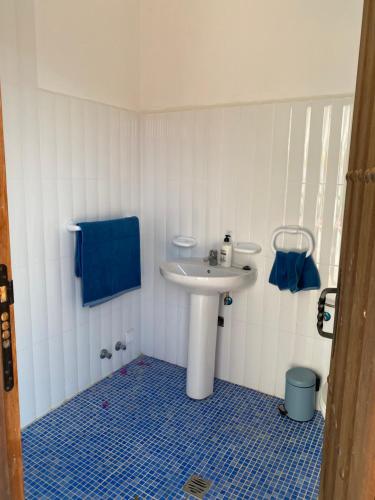 uma casa de banho com um lavatório branco e piso em azulejo azul em Cortijo Las Palmeras El Chorro em Álora