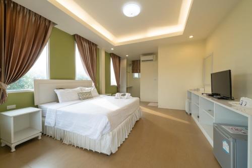 1 dormitorio con 1 cama blanca y TV en Banlomnow en Chiang Rai