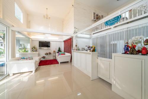 una gran sala de estar con muebles blancos y una gran ventana. en Banlomnow en Chiang Rai