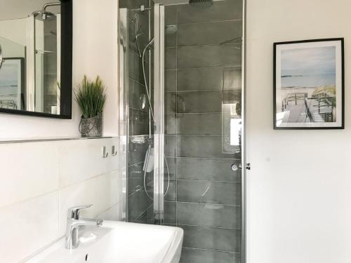 a bathroom with a shower and a sink and a mirror at Feriendorf Rugana - Komfortplus Appartement mit 1 Schlafzimmer A03 in Dranske