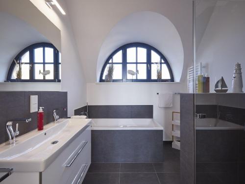 baño con 2 lavabos, bañera y 2 ventanas en Reetland am Meer - Premium Reetdachvilla mit 3 Schlafzimmern, Sauna, Kamin und Massagesessel F05, en Dranske