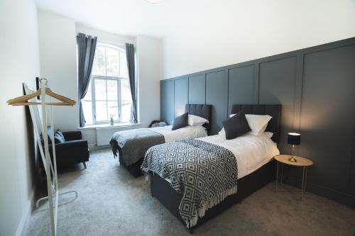 um quarto com 2 camas, uma cadeira e uma janela em Litton Mill Retreat, Luxury Converted Mill em Cressbrook