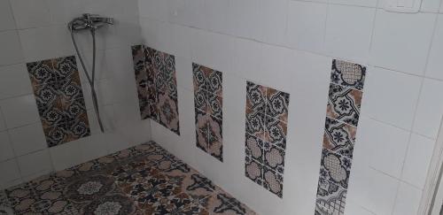 La salle de bains est pourvue d'une douche et de carrelage sur le mur. dans l'établissement Dar Mamina, à Sīdī ash Shammākh