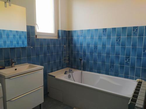 a blue tiled bathroom with a tub and a sink at La clef des champs - Gîte 9 personnes entre Lyon et St-Etienne in Les Halles