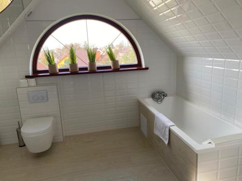 a bathroom with a tub and a toilet and a window at Gościniec Pod Lipą in Mikołajki
