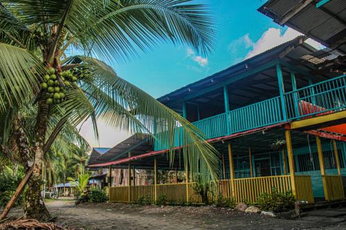 un edificio con una palmera delante de él en Refugio Mr Jerry Eco Hostal en Bahía Solano