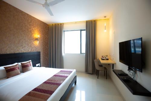 a hotel room with a bed and a television at Hotel Singh`s By WB Inn, Vashi, Navi Mumbai in Navi Mumbai