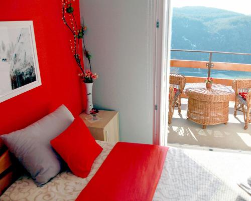 a bedroom with a red wall with a bed and a balcony at Biserna Dolina Uvac in Sjenica