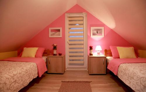 two beds in a attic room with pink walls at Biserna Dolina Uvac in Sjenica