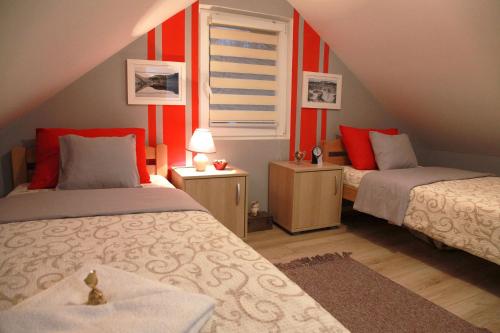 two beds in a room with red walls at Biserna Dolina Uvac in Sjenica