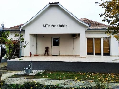 a white house with a sign on the top of it at Nita Vendégház in Solt