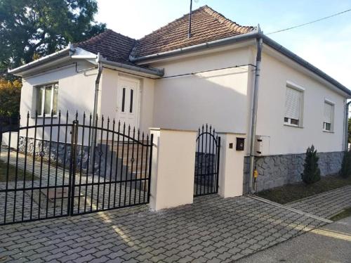 a white house with a gate in front of it at Nita Vendégház in Solt