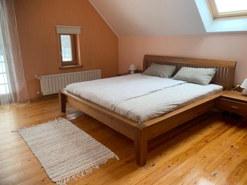 a large bed in a room with a wooden floor at Pie Ezerrozēm in Ķavari