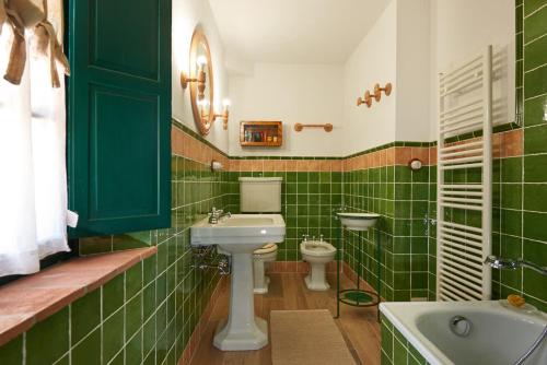 Baño de azulejos verdes con aseo y lavamanos en Casarossa, la casa del cuore, en Casciana Terme
