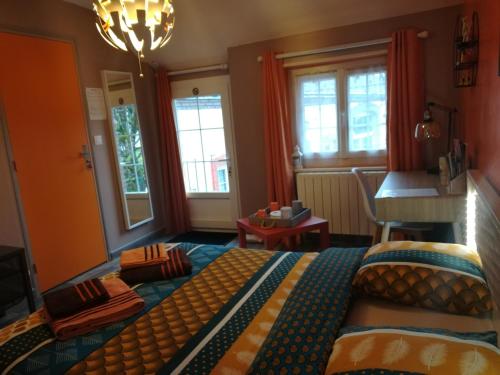 a bedroom with a bed and a table and windows at La cité des abeilles in Villemandeur
