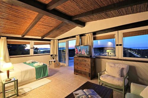 a bedroom with a bed and a tv and windows at Residence Balocco Porto Cervo in Porto Cervo