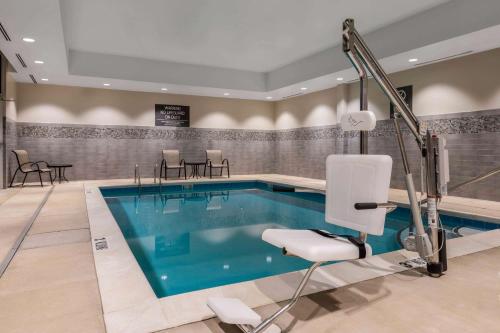 a swimming pool in a hotel room with a chair at La Quinta by Wyndham Greensboro Airport High Point in Greensboro