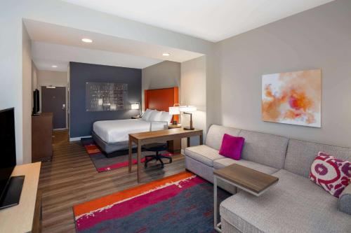 a hotel room with a bed and a couch at La Quinta by Wyndham Greensboro Airport High Point in Greensboro
