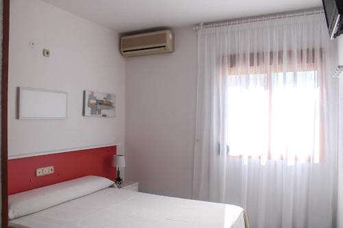 1 dormitorio con cama blanca y ventana en Hostal Las Dunas en Cabo de Gata