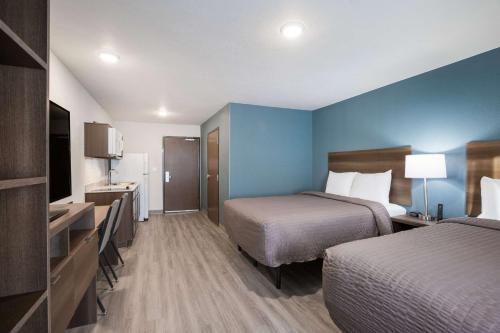 a hotel room with two beds and blue walls at WoodSpring Suites Detroit Madison Heights in Madison Heights