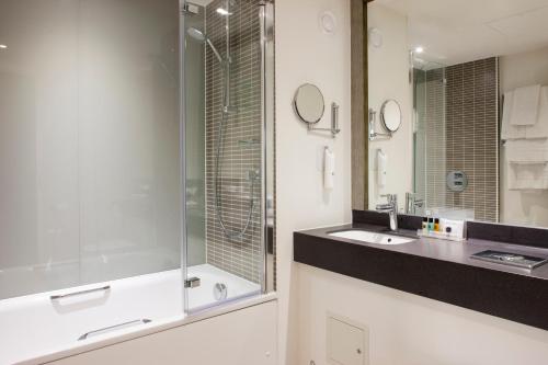 a bathroom with a sink, mirror, and bathtub at Holiday Inn Ipswich Orwell, an IHG Hotel in Ipswich