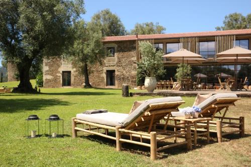 two lounge chairs and umbrellas in front of a building at Terra Rosa Country House & Vineyards in Ponte de Lima