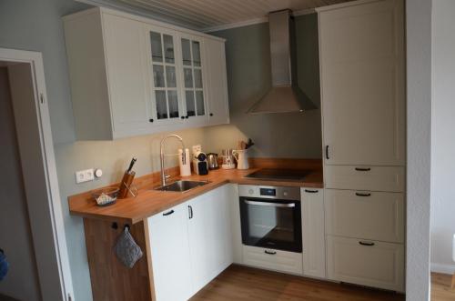una cocina con armarios blancos y fregadero en Harz-Butze en Sankt Andreasberg