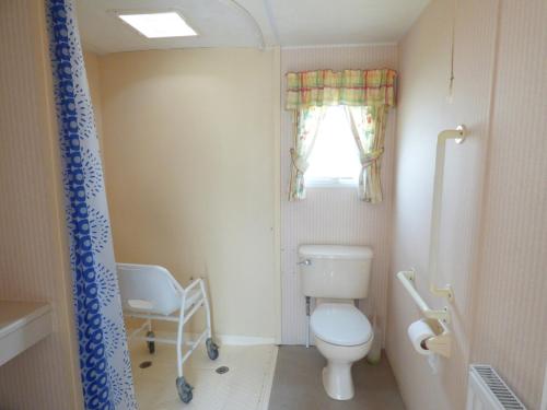 a small bathroom with a toilet and a window at DISABLED ACCESS Orchards 21 at Southview Leisure Park in Lincolnshire