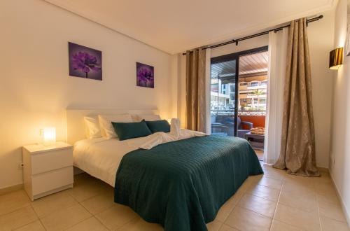 Schlafzimmer mit einem Bett mit grüner Tagesdecke in der Unterkunft Balcon de Los Gigantes 2A016 in Puerto de Santiago