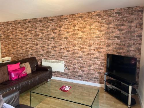 a living room with a couch and a tv and a brick wall at South Shore Road, Gateshead in Gateshead