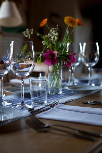 a table with wine glasses and a vase of flowers at Sahlströmsgården in Torsby
